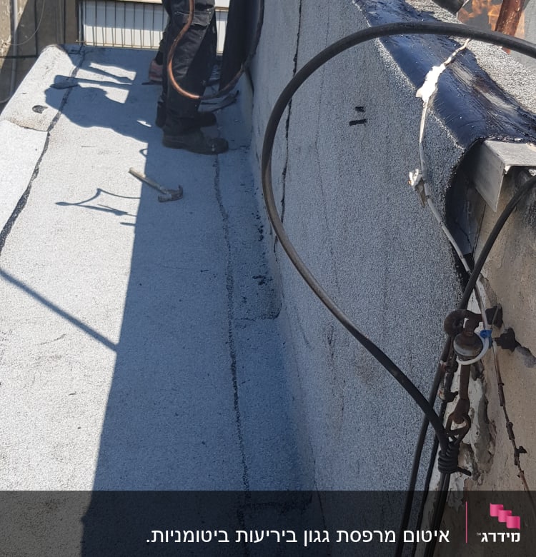 אדם מבצע איטום גג עם יריעות ביטומניות